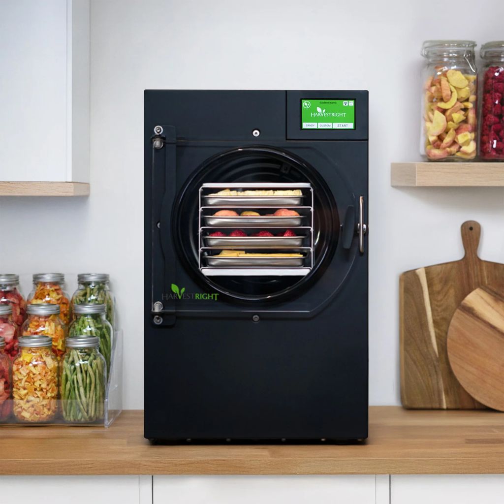 harvestright home freeze dryer black dehydrator on a kitchen counter with jars of dried fruits and vegetables in the background.