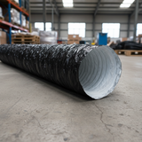 A black flexible PhonicTrap duct tube with a textured, crinkled exterior and a white ribbed interior, laid diagonally on a concrete floor inside a warehouse.