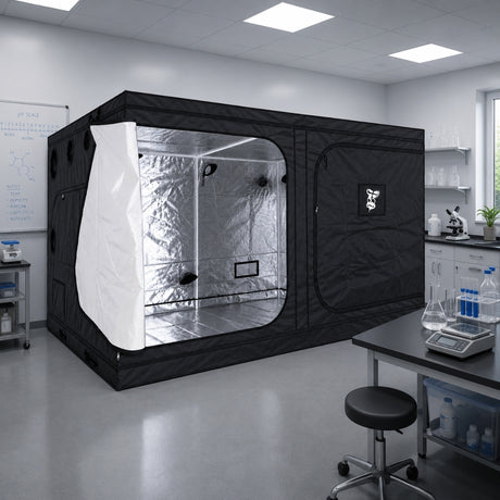 A black GorillaBox Deluxe grow tent measuring 4m-3m-2m with a reflective silver interior and a white front flap, set up in a clean laboratory or studio space with tables, cabinets, and equipment visible.