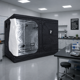 A black GorillaBox Deluxe grow tent measuring 5m-4m-2.2m with a reflective silver interior and a white front flap, set up in a clean laboratory or studio space with tables, cabinets, and equipment visible.