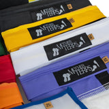 A close-up of several folded Mother Terps Bubble Bags stacked diagonally, showing the black woven Mother Terps logo patch on each bag. Visible bag colors include black, yellow, white, purple, red, orange, and blue, with small tan size tags.