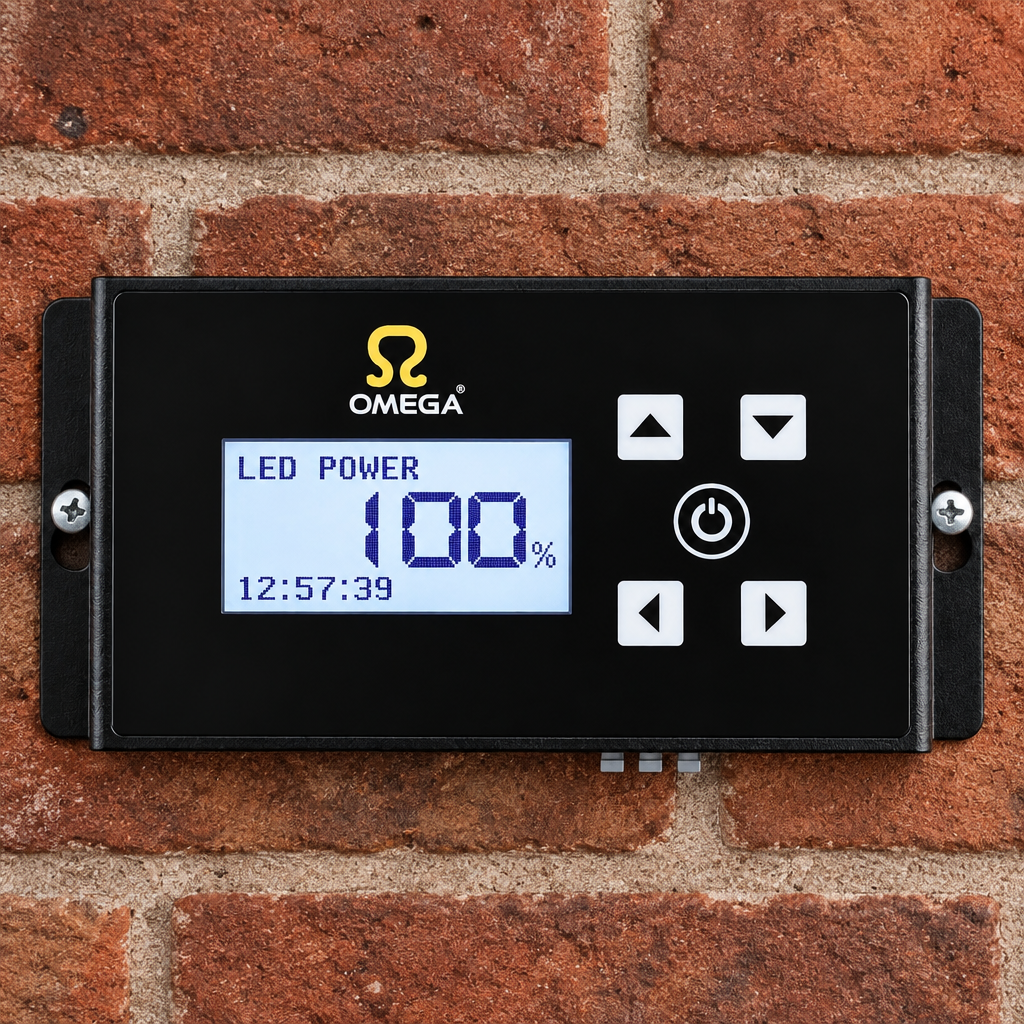 An Omega LED power controller with a black faceplate and blue backlit display, mounted on a red brick wall.