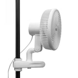 A white wall-mounted electric fan with a protective grille, attached to a white clamp on a black pole, shown against a solid white background.